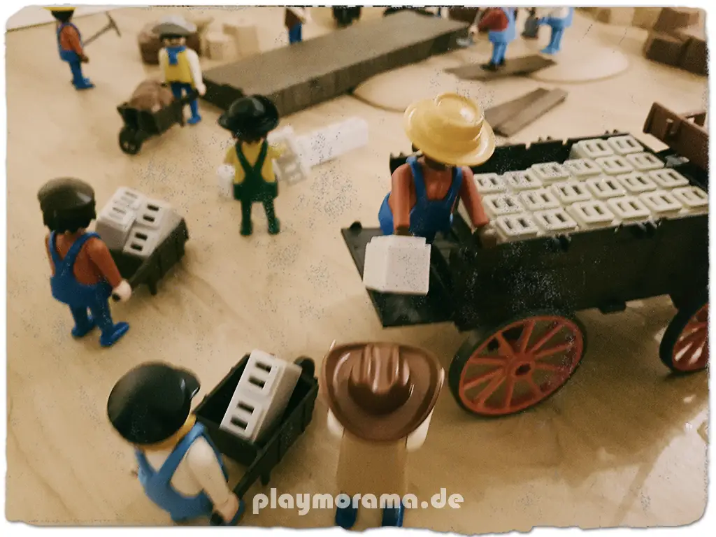 Eine Playmobil Western-Kutsche liefert Baumaterial. Arbeiter entladen Steine vom Wagen.