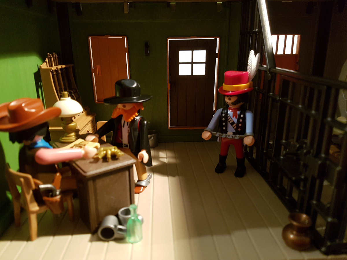 Playmobil Kopfgeldjäger übergibt Bandit an Sheriff. Der Sheriff freut sich über einen neuen Übernachtungsgast