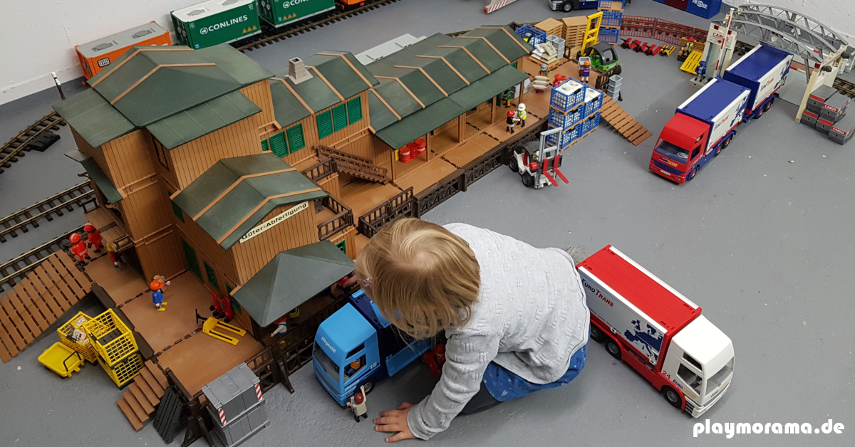 Kind spielt mit der Playmobil Güterabfertigung