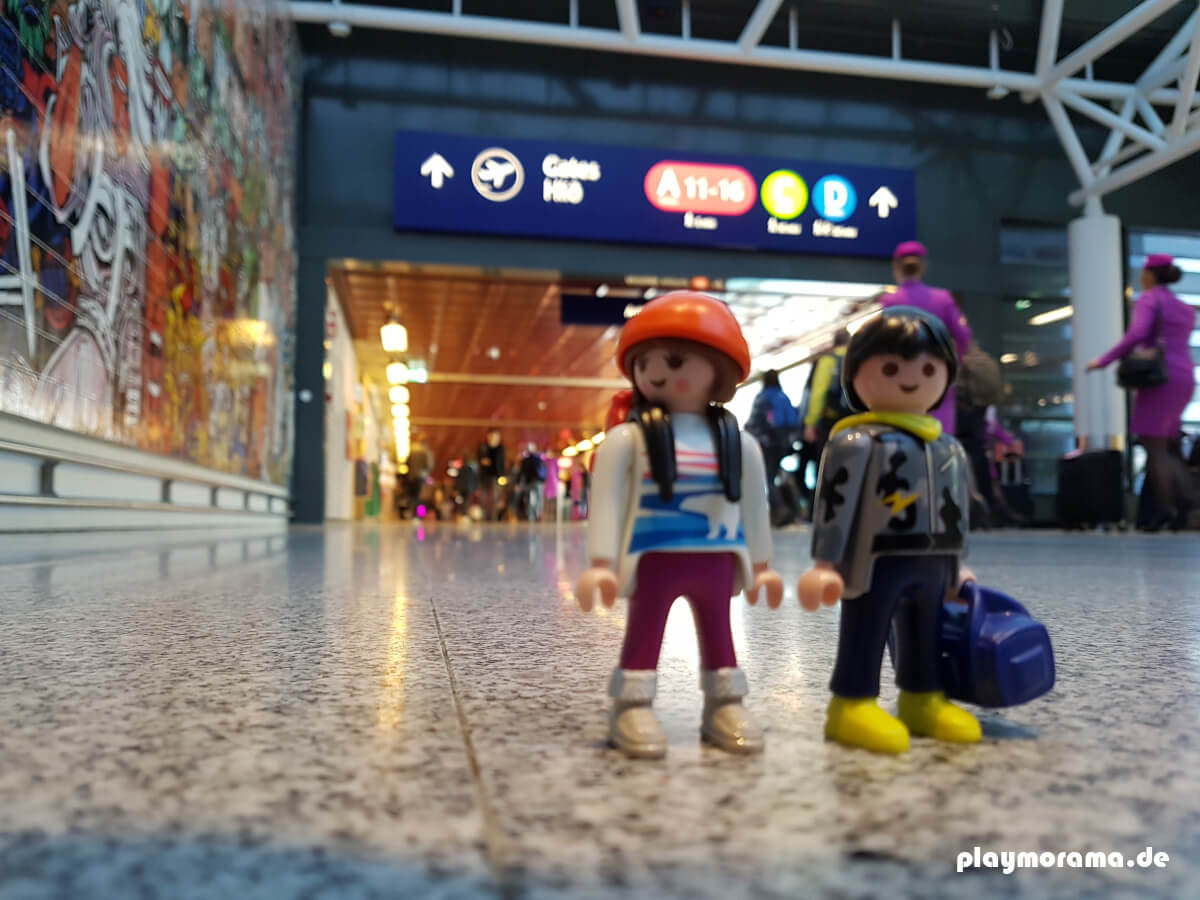 Playmobil Touristen nach Ankunft in Island am Internationalen Flughafen in Keflavik. Im Hintergrund sind Stewardessen von WOW-Air zu sehen.