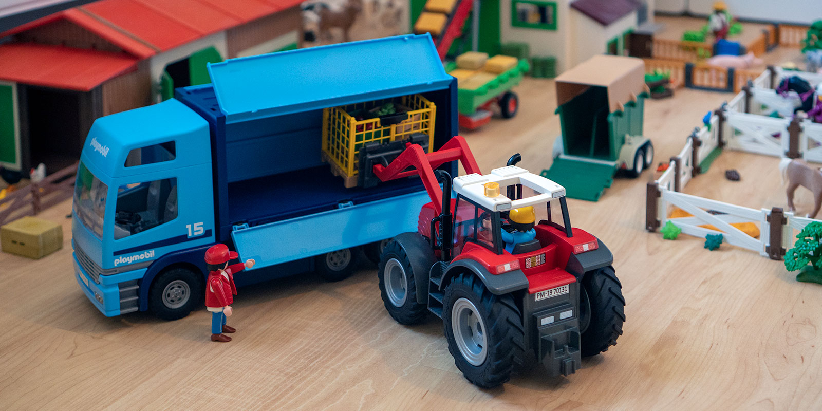 Playmobil Traktor belädt einen LKW mit Gemüsekiste.