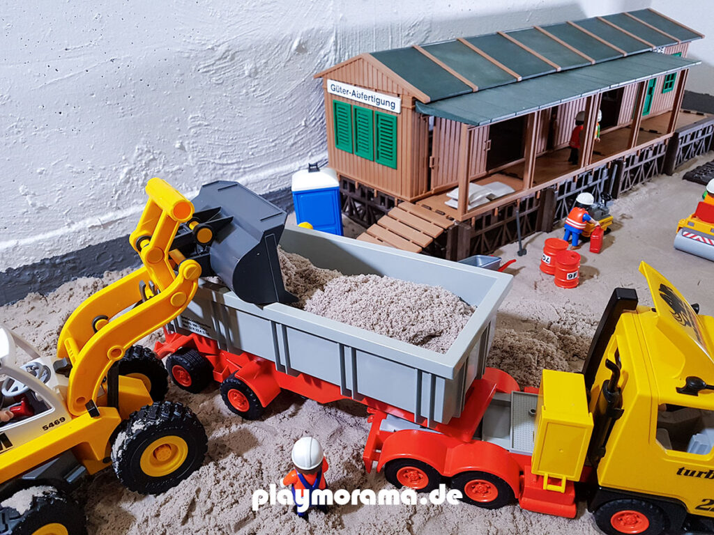 Baustellenkipper wird auf einer Baustelle von einem Radlader mit Sand beladen.
