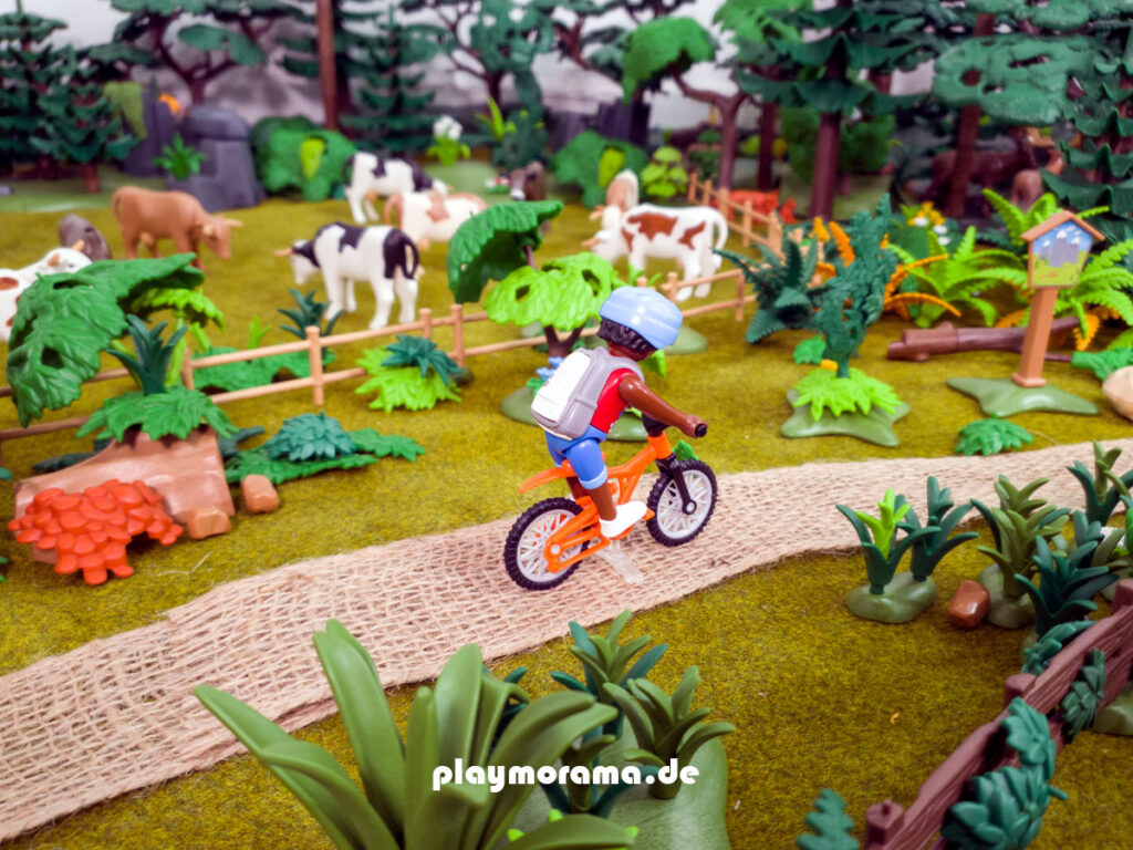 Playmobil Kühr auf der Weide. Ein Radfahrer fährt vorbei.