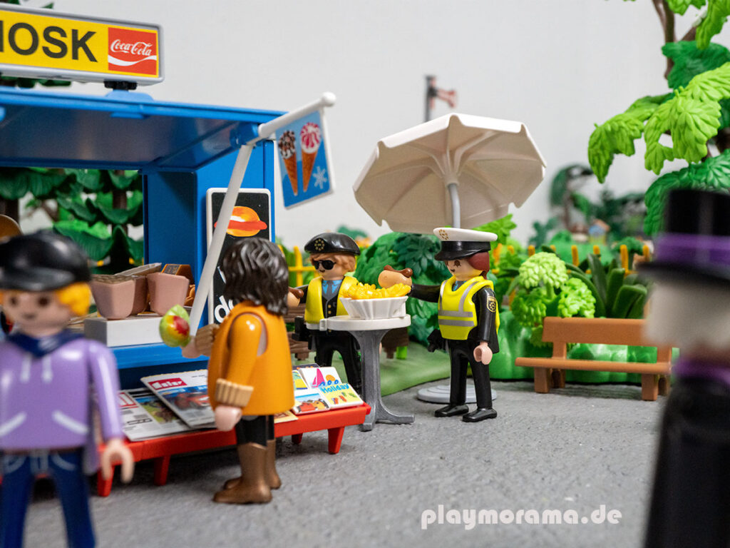 Zwei Zollbeamte essen ein Hotdog am Playmobil Kiosk.