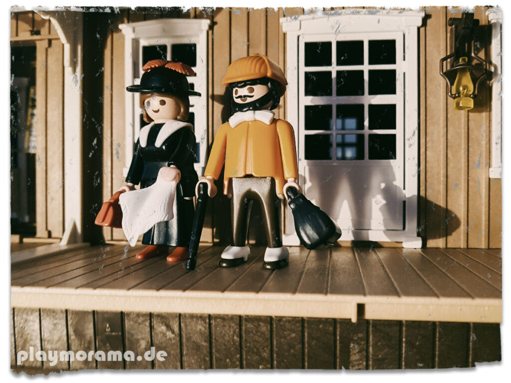 Reisender mit orangefarbenem Hut und orangefarbenem Sacko & Frau im schwarzen Kleid.