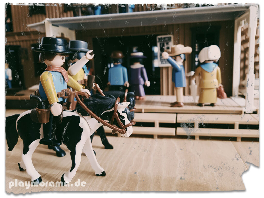 Cowboys von der Playmobil Silver Ranch reiten über die Hauptstraße vor dem Western-Bahnhof