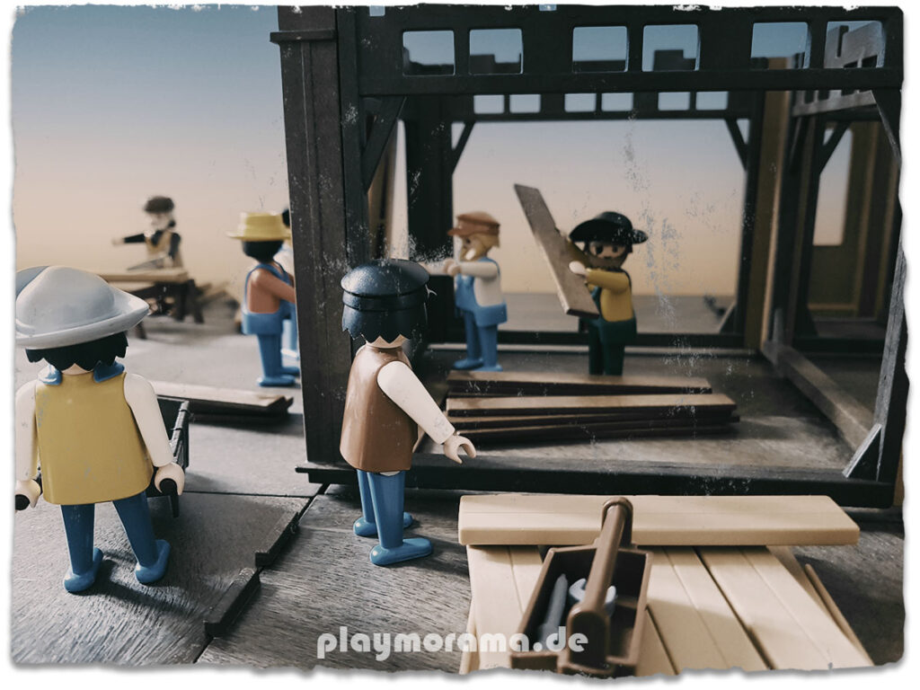 Bau der Playmobil Western Station. Eine Figur stapelt Holz.