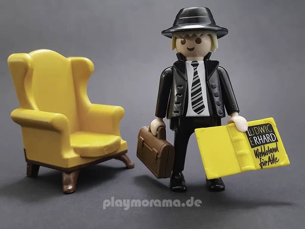 Playmobil Figur Ludwig Erhard mit Aktentasche, seinem Buch "Wohlstand für Alle" und seinem gelben Sessel.