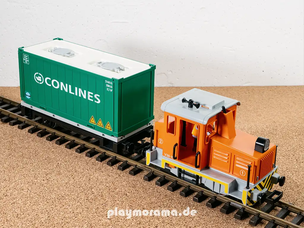 Orangene Rangierlok mit grünen Conlines-Containerwagen.