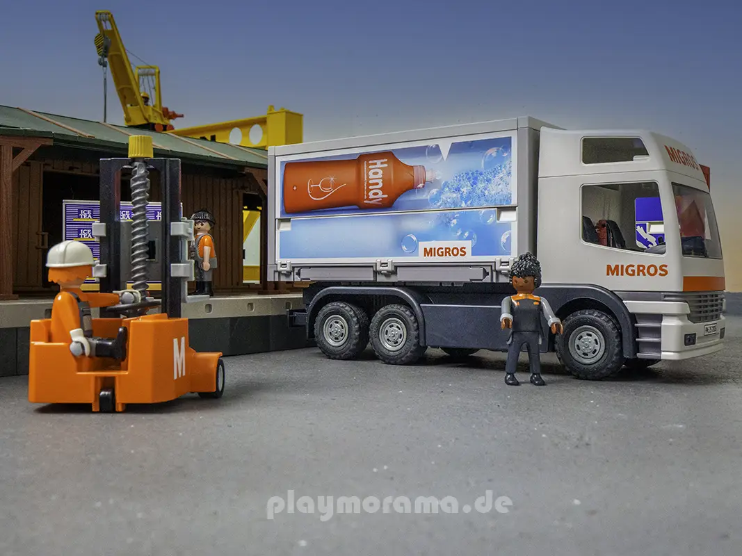 Migros-LKW mit Fahrerfigur und orangefarbenem Handstapler vor der PLAYMOBIL-Güterabfertigung