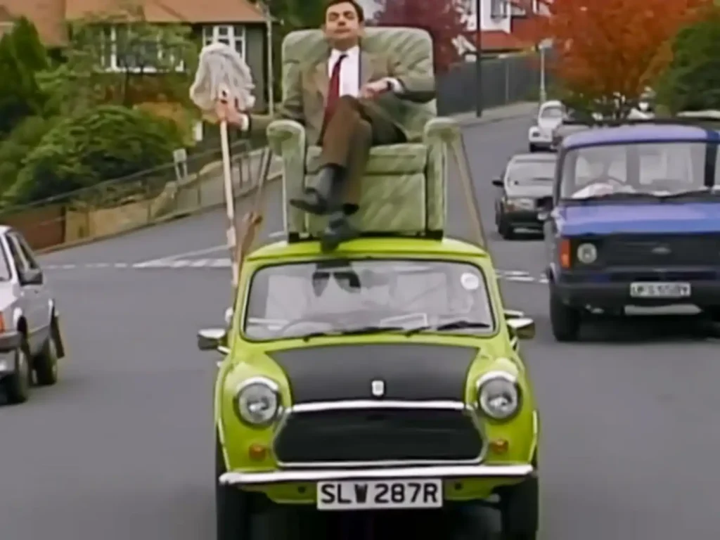 Mr. Bean steuert seinen Mini vom Sessel auf dem Dach aus.